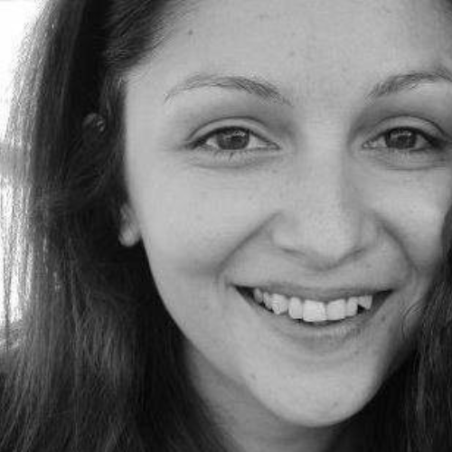 A black and white photo of a women with shoulder length brown hair, smiling at the camera.